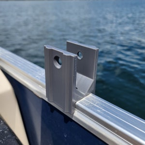 May include: A gray plastic bracket for mounting a boat accessory. The bracket is attached to a silver metal rail.