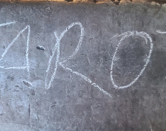 May include: A close-up of a grey concrete surface with the word "TAROT" written in white chalk.