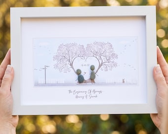 May include: A framed art print featuring a heart-shaped tree with two pebble figures. The artwork includes the date "16 04 22" and the text "The Beginning Of Always Harry & Sarah". The frame is white.