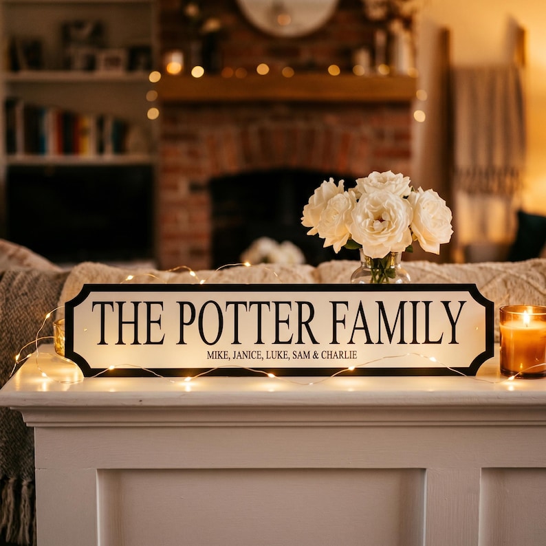 May include: A decorative sign with the text "THE POTTER FAMILY" in black lettering on a white background. The sign includes the names Mike, Janice, Luke, Sam & Charlie. A vase of white roses and a lit candle are nearby.