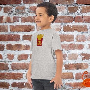 May include: A grey t-shirt with a graphic of french fries in a red box and the text "Fry Day!" printed on the front.