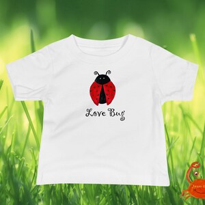 May include: White t-shirt with a red and black ladybug illustration and the text "Love Bug".