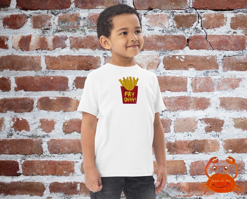 May include: White t-shirt with a red and yellow graphic of french fries in a red container with the text "Fry Day!" printed on the front.