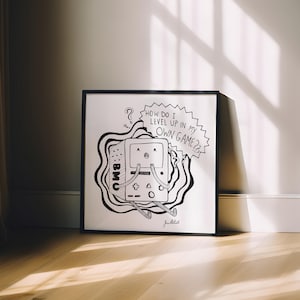 May include: Black framed art print featuring a cartoon-style video game console character with the text "HOW DO I LEVEL UP IN MY OWN GAME??" The artwork is in black and white, with the character surrounded by abstract lines.