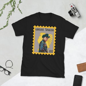 May include: Black t-shirt with a yellow and gray stamp design featuring a man in a cowboy hat and the text "Guasave. Sinaloa 011".
