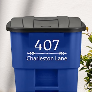 May include: Blue recycling bin with a white vinyl sticker that says "407 Charleston Lane" with a decorative arrow design.