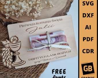May include: A wooden sign with the text "Pierwsza Komunia Święta Julii" and "OBFITYCH ŁASK BOŻYCH życzy Babcia i Dziadek". The sign also features a chalice and grapes, and a rolled-up bill of money tied with a white ribbon.