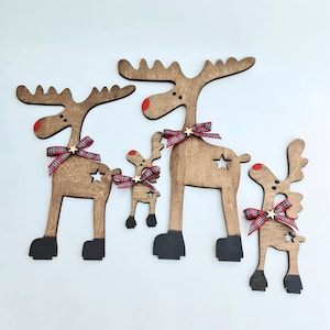 Set of four stained wooden reindeer figures of different sizes arranged on a white surface with star cutouts, red noses, and tartan ribbon bows, displayed next to vector format tags.