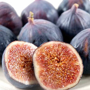 May include: A close-up of a group of ripe figs, some whole and some cut in half, revealing their sweet, red flesh and tiny seeds. The figs are a deep purple color and have a soft, velvety texture.