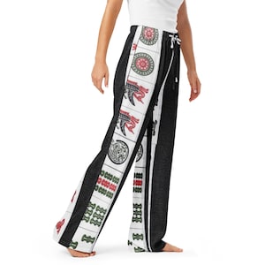 May include: Black and white patterned pajama pants with a drawstring waist. The pants feature a vertical white stripe with red, green, and black decorative designs. The pants are made of a soft, comfortable material.
