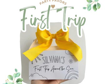 May include: A white gift box with a yellow ribbon and bow. The box has a black and white design with the text "Silvana's First Trip Around the Sun".