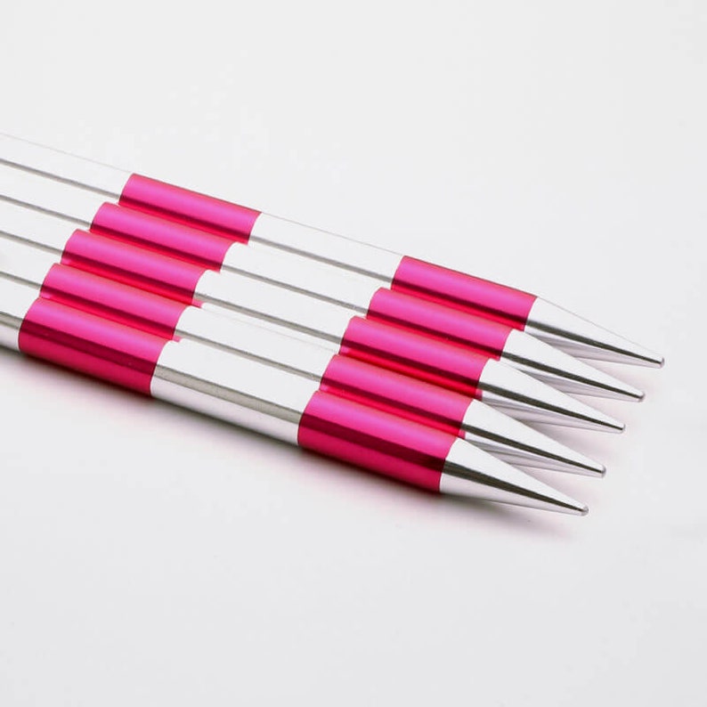 May include: Set of four silver and pink knitting needles. The needles are pointed and have a smooth finish.