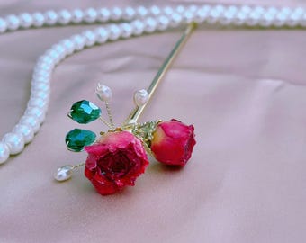 May include: A gold hair stick with two red rose buds and green crystal accents.