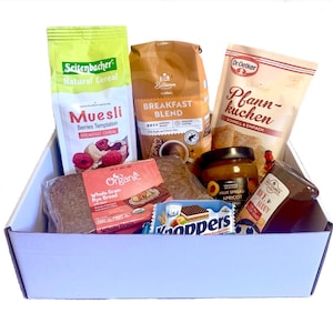 Pu&ograve; includere: Una scatola azzurra piena di prodotti per la colazione. Include un sacchetto di muesli, un sacchetto di caff&egrave;, una confezione di pancake, marmellata di albicocche, miele, pane di segale e wafer al cioccolato.