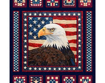 May include: A blue and white quilt with a bald eagle and an American flag in the center. The quilt is surrounded by a border of stars and stripes.