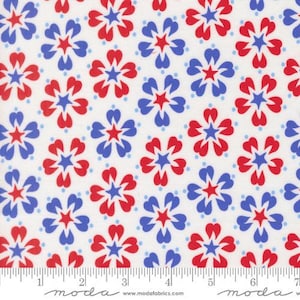 May include: A white fabric featuring a repeating pattern of stylized five-petaled flowers in alternating red and blue colors, each with a small star at the center. A ruler at the bottom shows measurements in inches up to 7 inches.