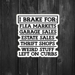 May include: A sticker with a cartoon pig wearing a sunflower and bow tie, with the text "I Brake For: Flea Markets, Garage Sales, Estate Sales, Thrift Shops, Weird Stuff, Left on Curbs." The sticker is on a black wooden background.