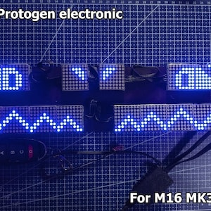 May include: Electronic display modules with blue LED lights, showing patterns and text. The modules are connected by black wires and a remote control. Text on the image reads "MK3 Protogen electronic" and "For M16 MK3 base".