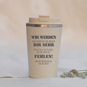 Könnte beinhalten: Ein beigefarbener Reisebecher mit passendem Deckel und silbernem Rand. Der Becher ist mit dunkelgrauem Text bedruckt: WIR WERDEN DICH VERMISSEN UND DANKEN DIR SEHR FÜR DIE TOLLE ZEIT! DU WIRST UNS AUF JEDEN FALL FEHLEN! UND WIR WÜNSCHEN DIR NUR DAS BESTE!
