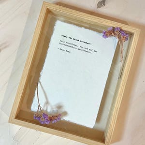 Könnte beinhalten: Ein gerahmtes Blatt Papier mit dem Text "Platz für Deine Botschaft"  "Dein Wunschtext, von uns auf der Schreibmaschine geschrieben."  "Dein Name" in einer einfachen schwarzen Schrift.