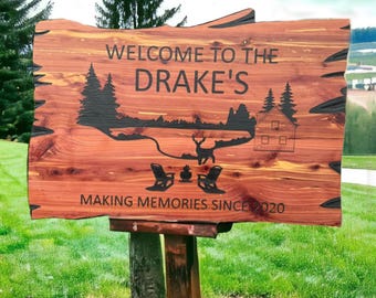 May include: A wooden sign with the text "Welcome to the Drake's Making Memories Since 2020" and a silhouette of a cabin, trees, a lake, and a deer.
