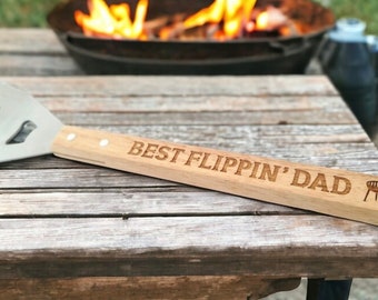 May include: A wooden spatula with a metal blade and a handle that says "BEST FLIPPIN' DAD" with a grill icon.