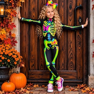 May include: A black long-sleeve jumpsuit featuring a neon green skeleton print with a pink butterfly on the chest and a yellow flower on the hip. The jumpsuit has a high neckline and is paired with a large, multi-colored rainbow hair bow.