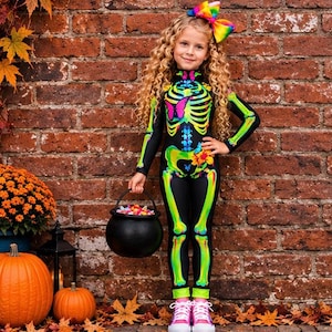 May include: A black long-sleeved jumpsuit featuring a vibrant neon green and blue skeleton print with pink butterfly accents on the chest and a yellow flower on the hip, paired with a large rainbow-colored hair bow and pink sneakers.