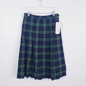 Pode incluir: Uma saia plissada até o joelho com um padrão xadrez em azul escuro e verde com linhas vermelhas finas. A saia está pendurada num cabide de plástico branco e inclui uma etiqueta retangular branca com o nome da marca Pendleton impresso.