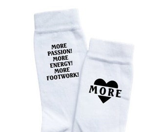 May include: White socks with black text that reads "More Passion! More Energy! More Footwork!" One sock has a black heart with the word "More" inside.