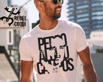 May include: White t-shirt with a black and white graphic of a man's face with the text "PEDRO ALMODOVAR" printed on it.
