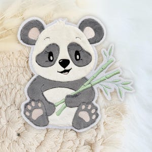 Könnte beinhalten: Ein grauer und weißer Pandabär, der einen Bund grüner Bambusstangen hält. Der Panda sitzt auf einem weißen Hintergrund.