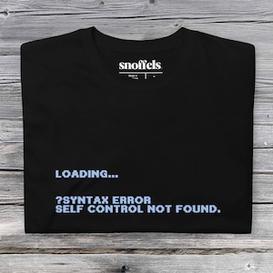 Op de afbeelding: Zwart T-shirt met een witte tekstgrafiek met de tekst "LOADING... ?SYNTAX ERROR SELF CONTROL NOT FOUND."