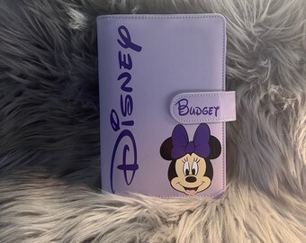 May include: Purple leather planner with a Disney logo and a Minnie Mouse image. The planner has a metal ring binder and a label that says "Budget".