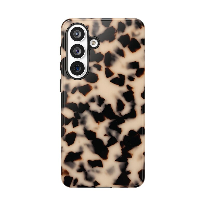 May include: A rectangular smartphone case featuring a tortoiseshell pattern with irregular black and dark brown spots scattered across a translucent beige background. The case includes a vertical cutout for a triple-lens camera system.
