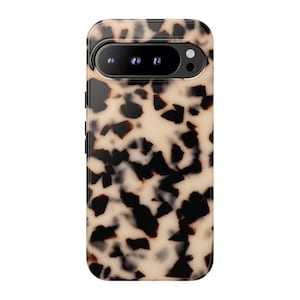 May include: A smartphone case featuring a glossy tortoiseshell pattern with irregular dark brown and black spots set against a creamy beige background. The case includes a horizontal cutout at the top for a triple camera system and flash.