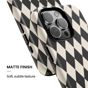 May include: A smartphone case featuring a black and cream diamond harlequin pattern with a matte finish. The case has a soft, subtle texture and includes cutouts for the camera lenses and side buttons. The text MATTE FINISH is visible.
