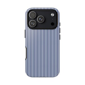 May include: A smartphone case featuring a vertical pinstripe pattern in dark blue and white. The case has a rectangular camera cutout at the top containing three circular lenses and a flash, with a black housing surrounding the camera components.