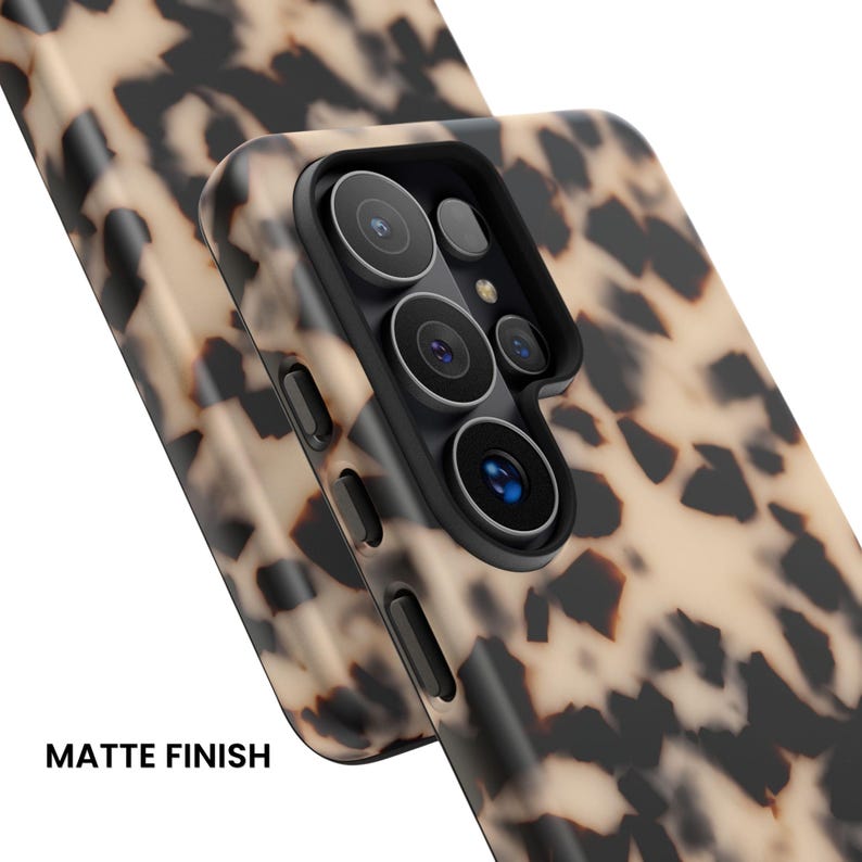 May include: A phone case with a beige and black tortoiseshell pattern and a matte finish. The case features a raised black camera cutout with multiple circular lens openings and side buttons. The text MATTE FINISH is visible.