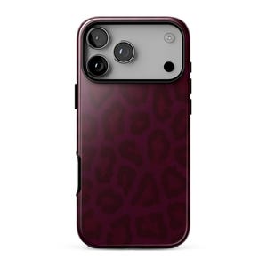 May include: A smartphone case featuring a dark burgundy and black leopard print pattern. The upper section of the case has a light gray rectangular camera cutout area with three circular lens openings and a small circular flash aperture.