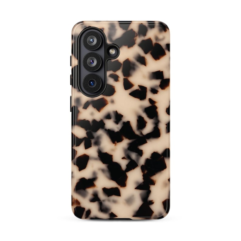 May include: A rectangular smartphone case featuring a high-contrast tortoiseshell pattern with irregular black and dark brown shapes set against a creamy beige background. The case includes a black camera module with three circular lenses.