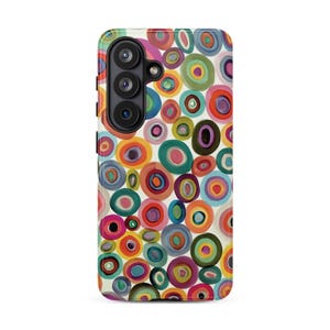 May include: A smartphone case featuring a vibrant, multi-colored pattern of concentric circles in shades of red, orange, yellow, green, blue, and purple against a white background, with a black camera module on the upper left side.