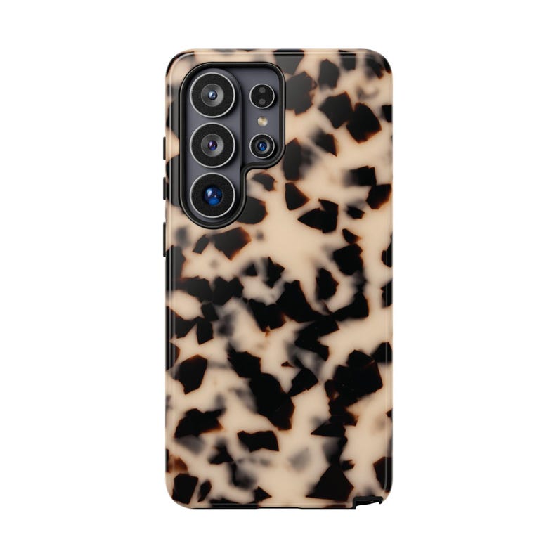 May include: A rectangular smartphone case featuring a beige and black tortoiseshell pattern. The case has a dedicated cutout section in the upper left corner to accommodate a multi-lens camera system with four circular lenses and a flash.