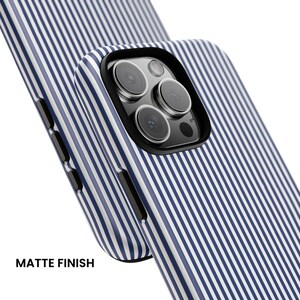 May include: A smartphone case featuring a blue and white vertical pinstripe pattern with a matte finish. The case has a black camera cutout frame and black side buttons, designed to fit a device with a triple-lens rear camera system.