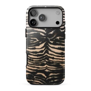 May include: A smartphone case featuring a black and beige tiger stripe pattern. The design covers the back of the case, which includes a rectangular cutout at the top for a triple camera system and a flash, showing a light grey camera housing.