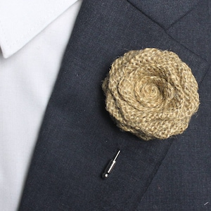 May include: A brown burlap flower boutonniere with a silver pin.