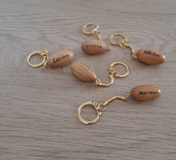Personalized wooden rugby ball-shaped keychains.