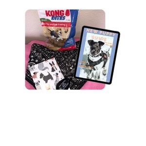 May include: A black and white bandana with a black and white dog illustration, a bag of Kong dog treats, and a New Puppy Guide booklet with a black and white puppy wearing a harness.
