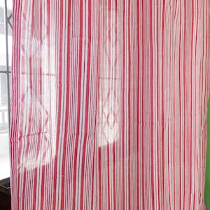 May include: A red and white striped curtain or fabric. The vertical stripes create a bold pattern. The material appears to be lightweight and slightly see-through, with some creases visible. The overall effect is simple and visually striking, suitable for home decor.