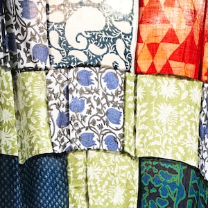 Könnte beinhalten: Ein Patchwork-Textil mit quadratischen Stoffstücken in verschiedenen Mustern. Die Designs umfassen Blumen, Paisley und geometrische Formen in Blau, Grün, Rot und Weiß. Das Material wirkt leicht, möglicherweise Baumwolle oder Leinen, für eine abwechslungsreiche Komposition.